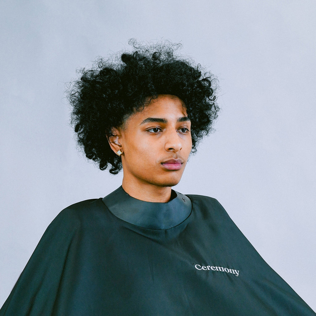 Black Ceremony Stylist Cape with an adjustable strap on a person