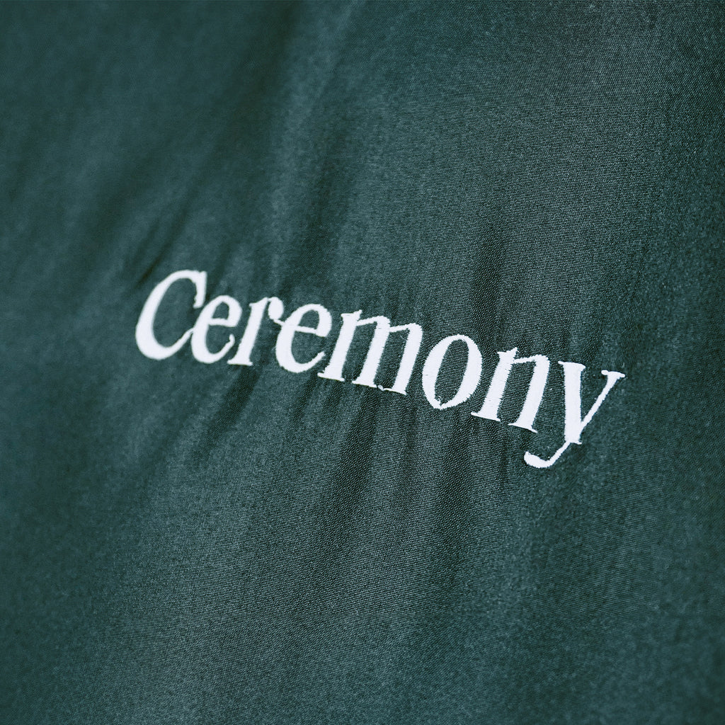 Embroidered Logo close-up of a Black Ceremony Stylist Cape with an adjustable strap