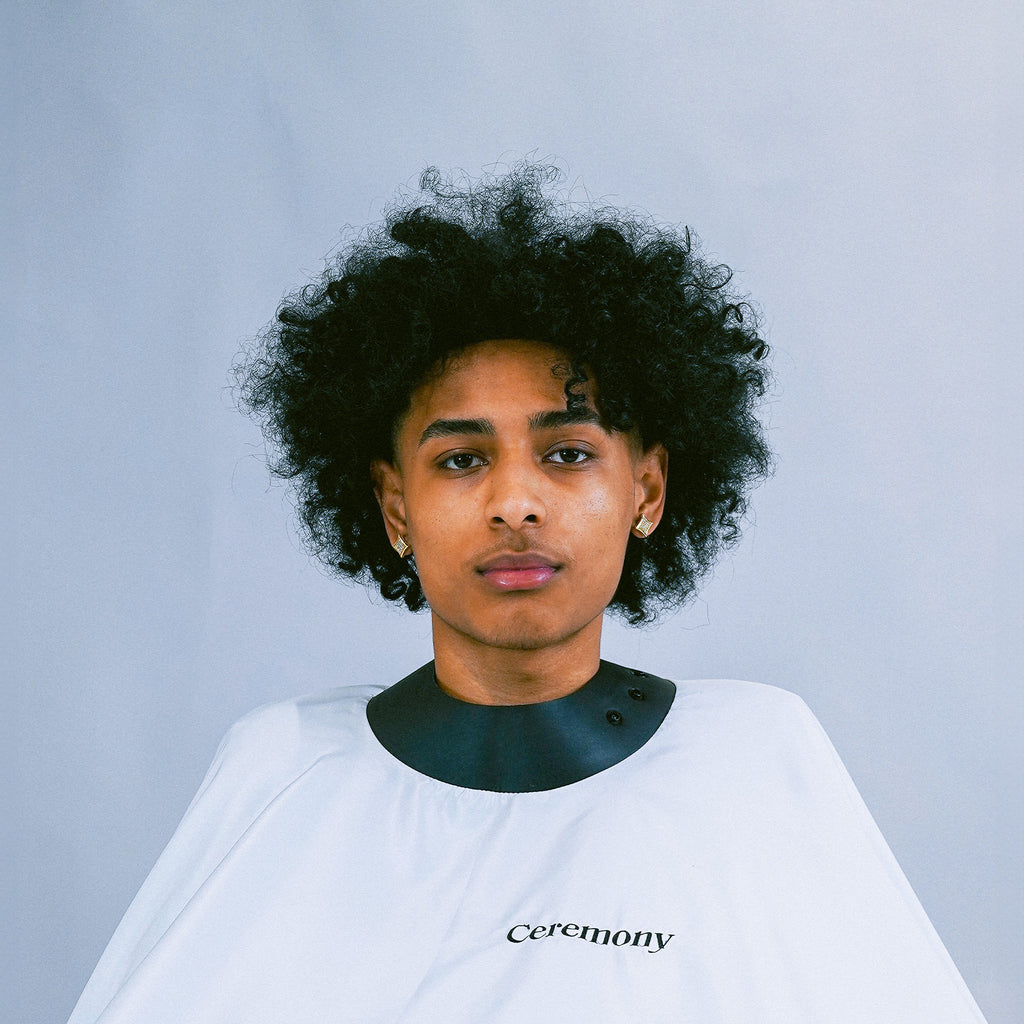 White Ceremony Stylist Cape with an adjustable strap on a person